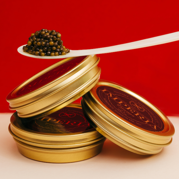 three tins of imperia caviar on red background with spoon